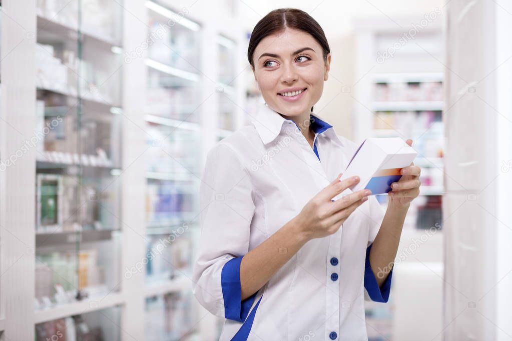Happy female pharmacist supervising drugs