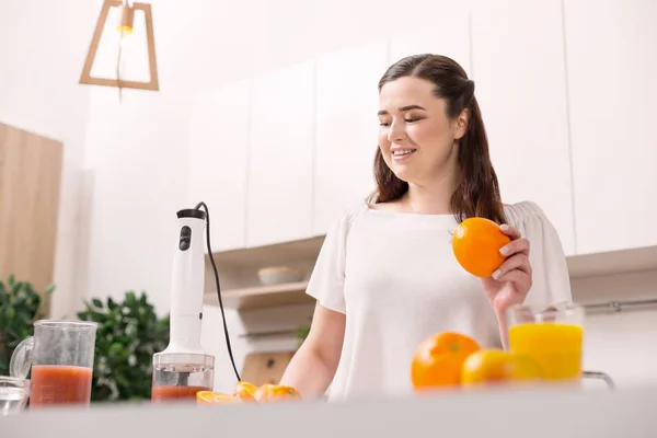 Feliz mujer alegre exprimiendo naranja fresca — Foto de Stock