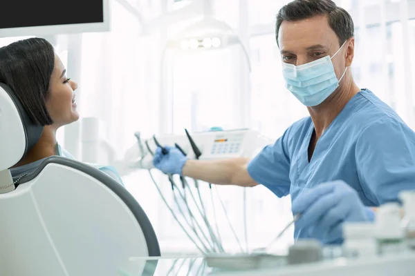 Ernstige mannelijke tandarts houden een instrument — Stockfoto