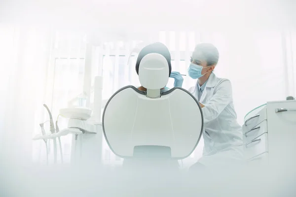 Serious female dentist examining her patients teeth