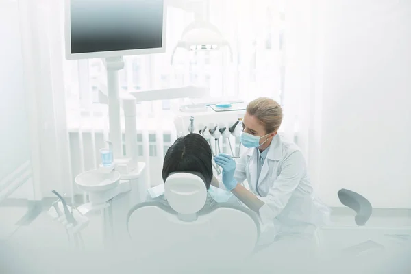 Dentista femenina inspirada examinando los dientes de sus pacientes — Foto de Stock