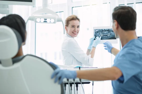 Glada tandläkare visar tänder på skärmen — Stockfoto