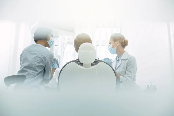 Inspired dentists sitting near the patient