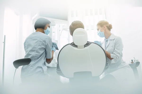 Experienced dentists sitting near the patient — Stock Photo, Image