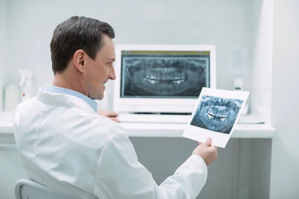 Vrolijke mannelijke tandarts houden van een afbeelding — Stockfoto