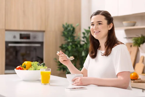 Donna entusiasta riflettente mangiare porridge — Foto Stock