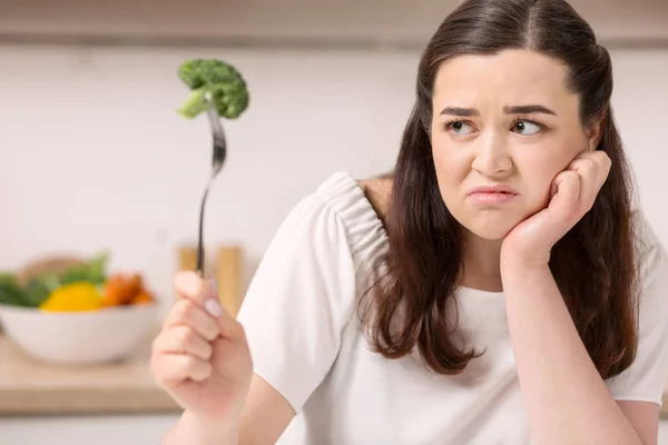Irritada mulher sombria comendo brócolis — Fotografia de Stock