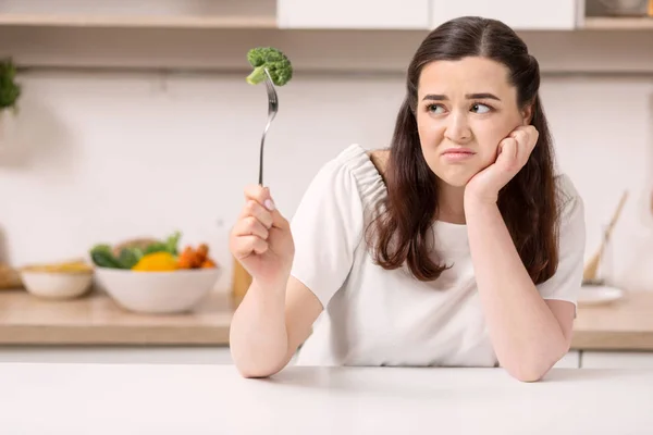 Displeased beautiful woman eating vegetables — Stock Photo, Image