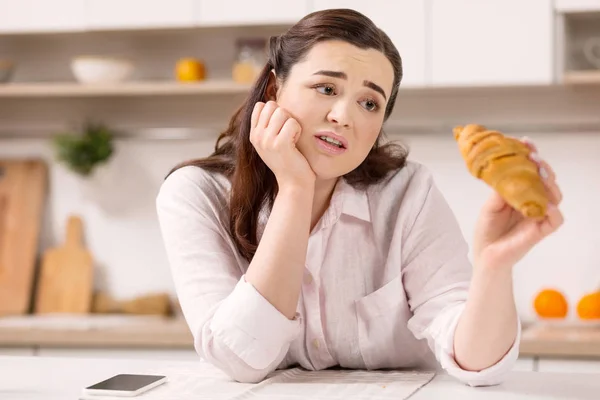 Deprimida mujer sombría lamentándose de croissant — Foto de Stock