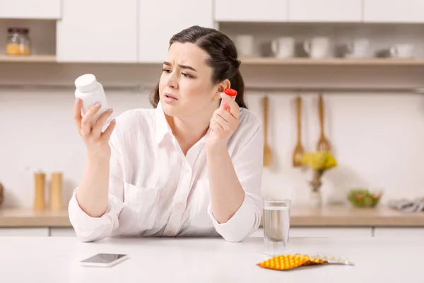 Concerned pretty woman selecting drugs — Stock Photo, Image