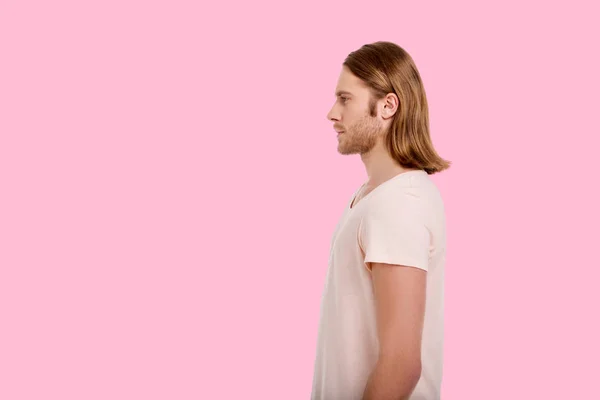 Приємний чоловік стоїть збоку на рожевому фоні — стокове фото