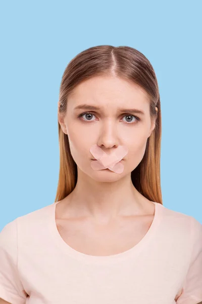 Sad woman having mouth shut with adhesive bandages — Stock Photo, Image