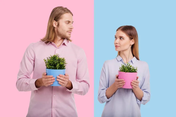 Giovane coppia che tiene vasi di fiori e si guarda a vicenda — Foto Stock