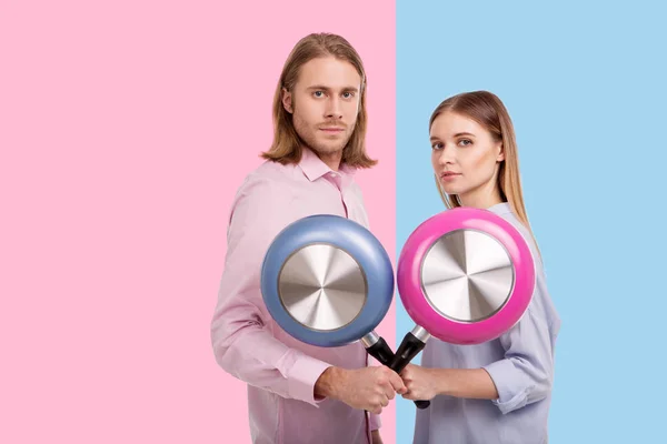 Pleasant couple posing with frying pans crossed — Stock Photo, Image