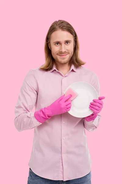 Χαρούμενος νεαρός άνδρας, θέτοντας κατά τον καθαρισμό ένα πιάτο — Φωτογραφία Αρχείου
