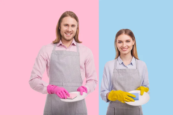 Jovem casal alegre limpando pratos e sorrindo — Fotografia de Stock