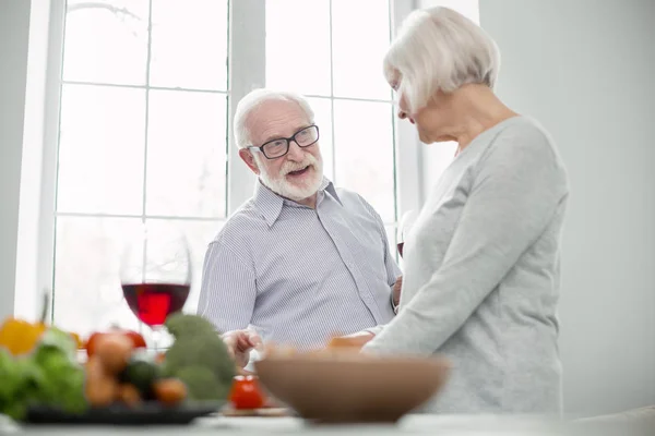 Pleasant aged couple cooking dinner