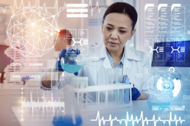 Bir şişe tutan ve sıvılar dökme dikkatli laboratuvar asistanı