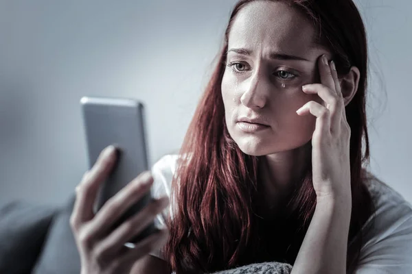 Sorrowful deplorable woman using phone — Stock Photo, Image