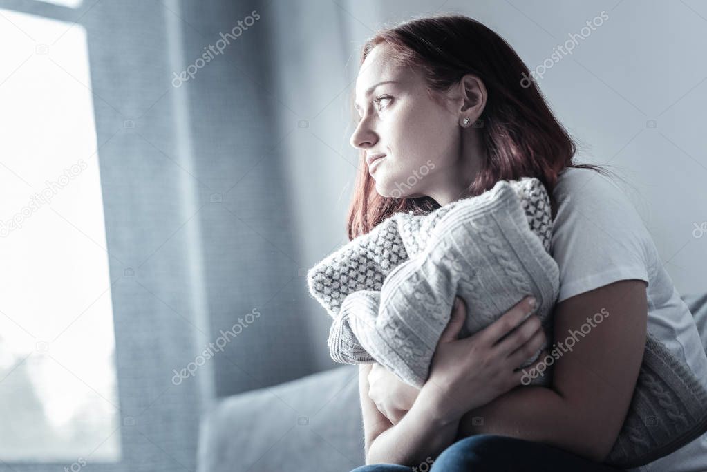 Hopeful melancholy woman embracing pillow