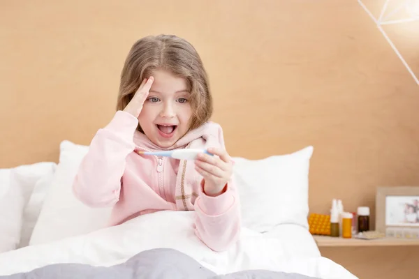 Ill child holding a thermometer — Stock Photo, Image