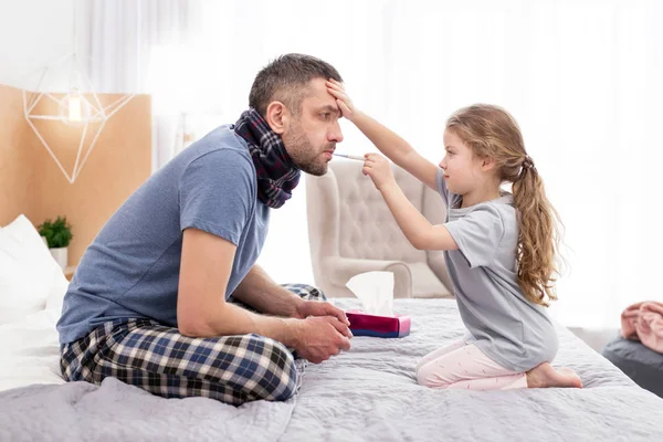 Menina concentrada tratando seu pai doente — Fotografia de Stock