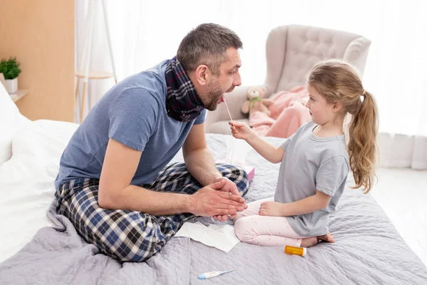 Chica cariñosa examinando a su papá enfermo — Foto de Stock