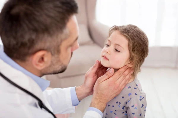 Médico serio examinando el cuello de las niñas — Foto de Stock