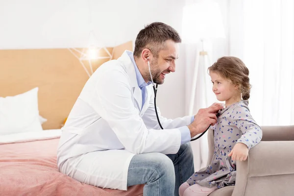 Docteur souriant à l'écoute des filles battements de coeur — Photo