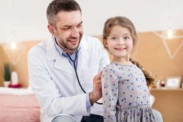 Happy general practitioner listening the girls heartbeat — Stock Photo, Image