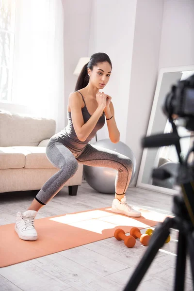 Athletic woman recording herself while doing squats — Stock Photo, Image