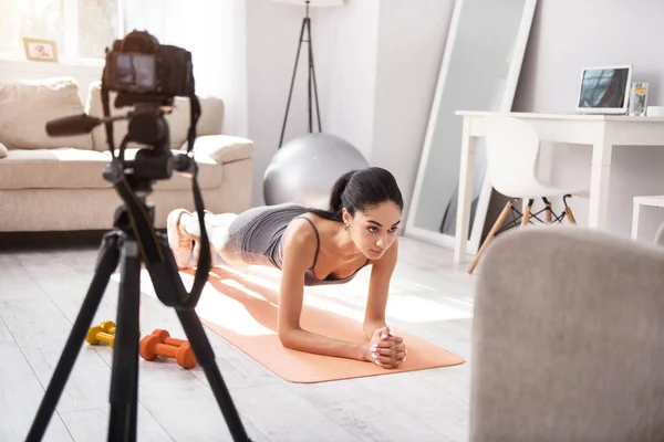 Атлетичная молодая женщина делает упражнения на доске и снимает себя — стоковое фото