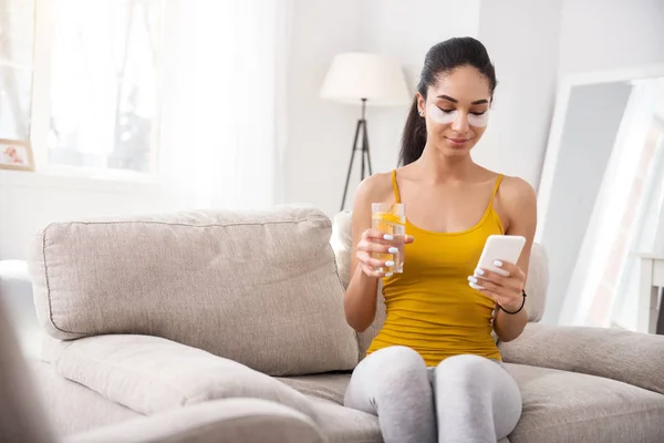 Vacker kvinna läsa textmeddelanden och dricksvatten — Stockfoto