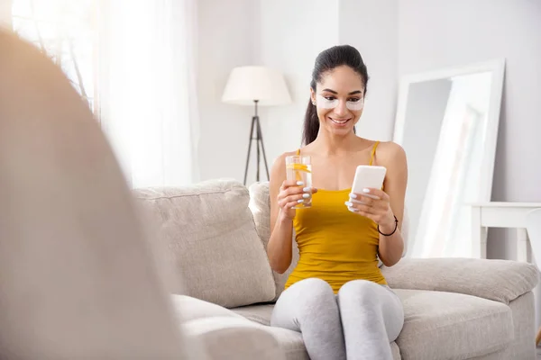 Cheerful woman texting and drinking water — Stock Photo, Image