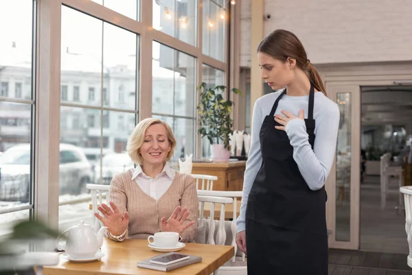 Una nueva camarera sin experiencia hablando con su cliente — Foto de Stock