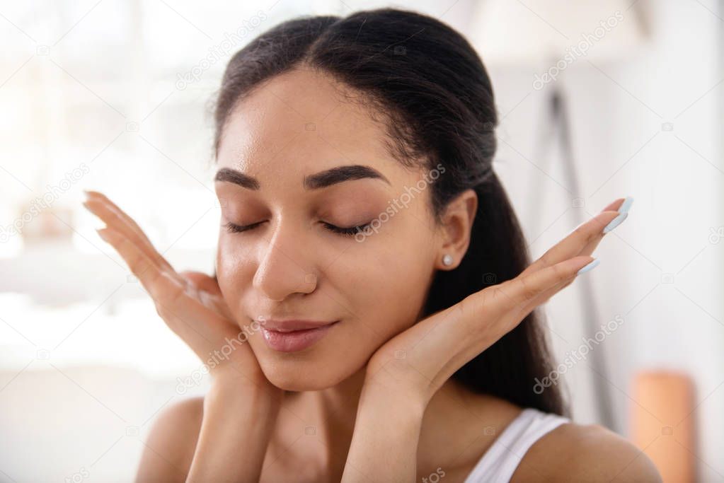 Close up of young woman massaging her face