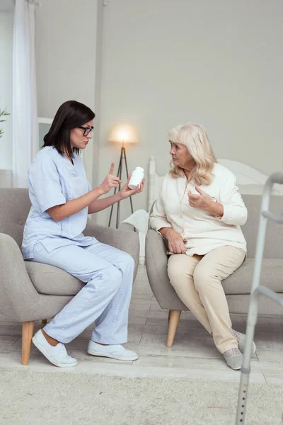 Serious caregiver convincing elder woman — Stock Photo, Image