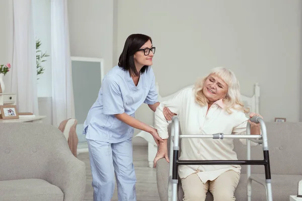 Angenehme Krankenschwester bietet ältere Frau Hilfe an — Stockfoto