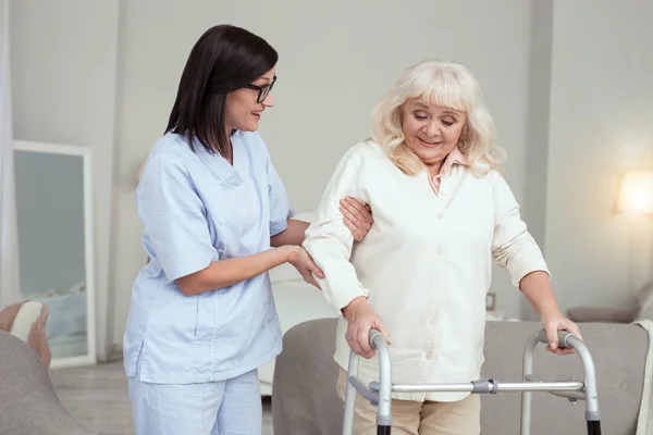 Gladlynt sköterska tar hand om äldre kvinna — Stockfoto
