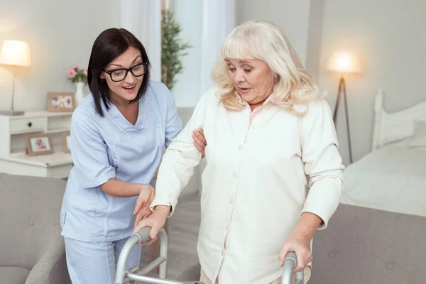 Positieve verpleegster komen met steun aan oudere vrouw — Stockfoto