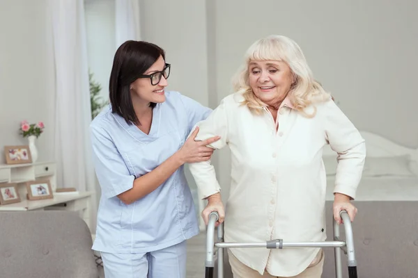 Радостная медсестра, обеспечивающая поддержку пожилой женщины — стоковое фото