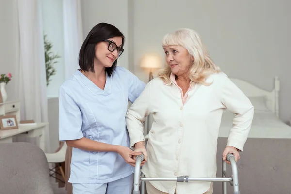 Charmante verpleegkundige vergemakkelijken van oudere vrouw leven — Stockfoto