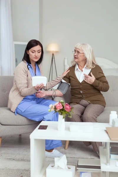 Pretty female caregiver watching blood pressure changes — Stock Photo, Image