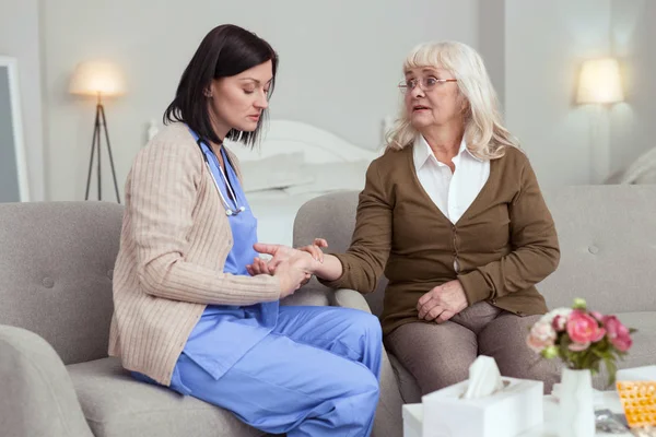 Focused female caregiver monitoring pulse — Stock Photo, Image