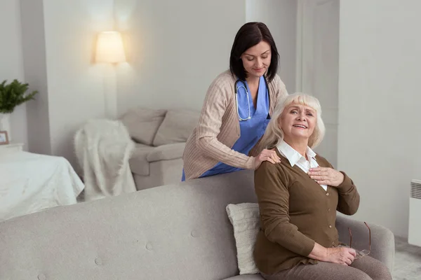 Enfermeira atenta massageando mulher mais velha de volta — Fotografia de Stock
