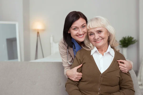 Enfermera alegre abrazando a la anciana — Foto de Stock