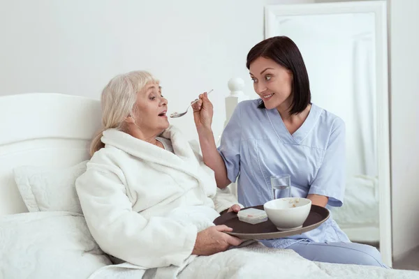 Cuidador feliz alimentando a la anciana —  Fotos de Stock