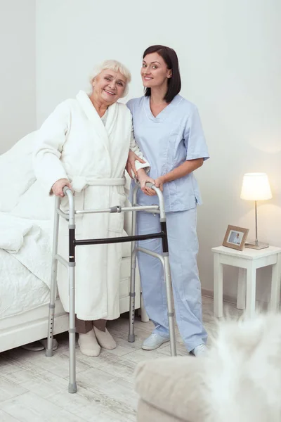 Mulher mais velha alegre andando com caminhante — Fotografia de Stock