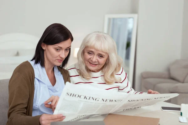 Щаслива літня жінка і доглядач вивчають газету — стокове фото
