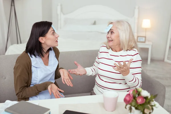 Joyful elder woman and caregiver guessing character — Stock Photo, Image